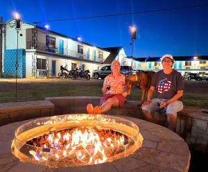a group of three people sitting next to a fire pit at Roadrunner Lodge Motel in Tucumcari