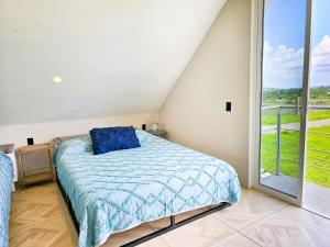 a bedroom with a bed and a large window at Blue House near Tolantongo Caves in San Miguel
