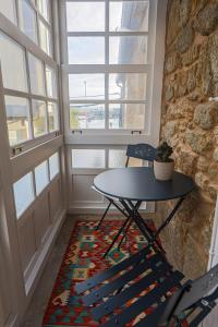 a table and chairs in a room with windows at Do Bico Rooms in Camariñas