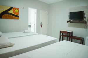 ein weißes Zimmer mit zwei Betten und einem Stuhl in der Unterkunft Hotel Visconde in Sobral