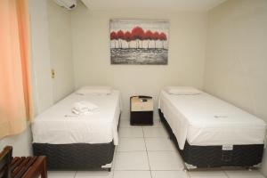 Zwei Einzelbetten in einem Zimmer mit einem Gemälde an der Wand in der Unterkunft Hotel Visconde in Sobral + 112 Fotos