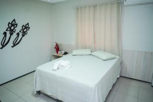ein Schlafzimmer mit einem weißen Bett, auf dem Handtücher liegen in der Unterkunft Hotel Visconde in Sobral
