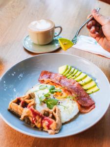 a plate of breakfast food with eggs bacon and cheese at Calle Flora Hotel by Jalo in Medellín
