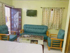 a living room with a couch and chairs and a tv at The Cruze - Premium Hotel in Gulzārbāgh