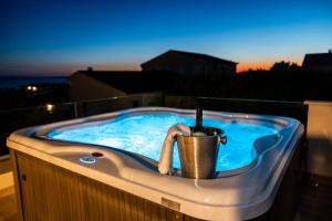 a hot tub with a bucket and a bottle of wine at LUXURY MANDRE HOUSE in Mandre