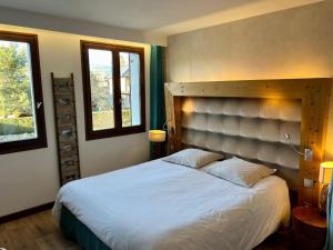 a bedroom with a large bed and two windows at Logis Hôtel - Auberge les Clarines in Le Châtelard