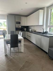 a kitchen with white cabinets and a table and chairs at Appartamento relax 5-4-3 in Rivalta Bormida