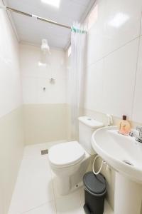 a white bathroom with a toilet and a sink at Hotel COP 30 in Belém