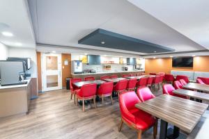 a restaurant with red chairs and tables and a bar at Comfort Suites in London