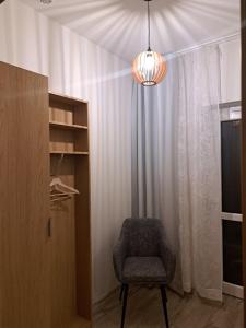 a chair in a room with a curtain and a chandelier at Dolina Miodu - Agro Kaszuby, Sauna, Balia in Borowina