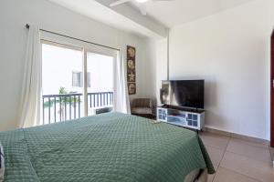 a bedroom with a bed and a tv and a window at Novus Mare, Cabarete center! in Cabarete