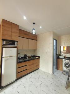 a kitchen with wooden cabinets and a white refrigerator at Blue Wave Surf House in Mirleft