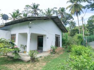 a white house with a porch and palm trees at Vinal Inn Midigama in Midigama East