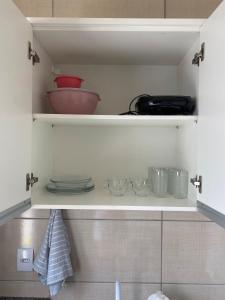 a cupboard with plates and bowls and dishes on it at Ap3 - Studio Confortável e Tranquilo in Guaíra +12 photos