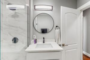 a white bathroom with a sink and a mirror at Group-Friendly Michigan City Home Near Beach! in Michigan City +16 photos