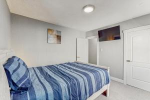 a bedroom with a bed with a blue and white striped comforter at Group-Friendly Michigan City Home Near Beach! in Michigan City