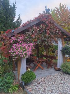 a gazebo covered in flowers with a picnic table at Domek pod lasem in Majdan Stulenski +14 photos