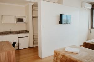 a white room with a kitchen and a table and a counter at Hotel Letto Caxias in Caxias do Sul