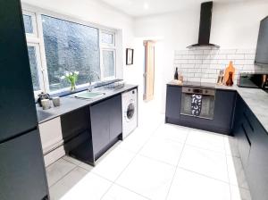 a large kitchen with a sink and a dishwasher at Urban Escape Stylish 3BR in Swansea in Swansea