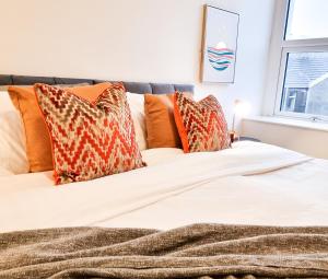 a bed with orange and white pillows on it at Urban Escape Stylish 3BR in Swansea in Swansea