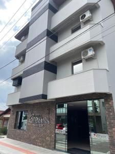 a tall white building with a window at Hotel Germânia Nova Veneza in Nova Veneza