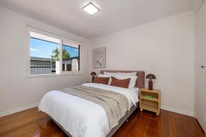 a white bedroom with a large bed and a window at Sundance steps to Half Moon Bay in Black Rock North