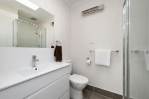 a white bathroom with a sink and a toilet at Sundance steps to Half Moon Bay in Black Rock North +19 photos
