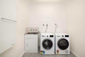 a white laundry room with a washer and dryer at Sundance steps to Half Moon Bay in Black Rock North