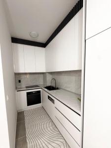 a kitchen with white cabinets and a carpeted floor at Stan na dan Lana in Vranješ
