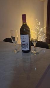 a bottle of wine and two wine glasses on a table at Stan na dan Lana in Vranješ +3 photos