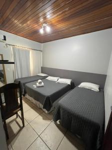 a room with two beds and a chair in it at Hotel Germânia Nova Veneza in Nova Veneza