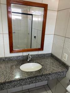 a bathroom counter with a sink and a mirror at Hotel Germânia Nova Veneza in Nova Veneza +20 photos