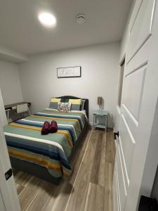 a bedroom with a bed with a striped blanket at Fowler Road Cozy Lower Suite in Airdrie