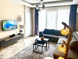 a living room with a couch and a tv at Theos Holiday Apartments Room 23 Family Suit Accommodation For Families Only in Kuşadası