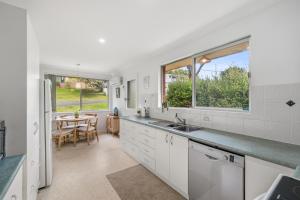 a kitchen with a sink and a table and windows at Salt & Sand - Flynn's Beach in Port Macquarie