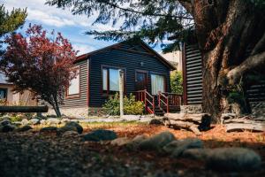 a log cabin with a tree in front of it at Paraiso Patagónico Bungalows and Aparts in El Calafate