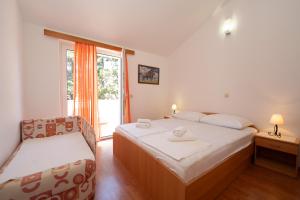 a bedroom with two beds and a chair and a window at Apartmani Kaštel in Stara Novalja