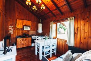 a kitchen with wooden walls and a white table and chairs at Paraiso Patagónico Bungalows and Aparts in El Calafate