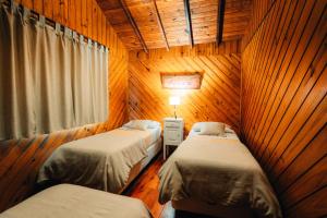 two beds in a room with wooden walls at Paraiso Patagónico Bungalows and Aparts in El Calafate
