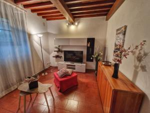 a living room with a red chair and a television at Villa Castaldi Firenze vicina al centro in Florence