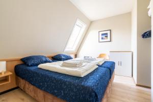 a bedroom with a bed with blue sheets and a window at Appartement De Bosrand, Resort Amelander Kaap in Hollum +50 photos
