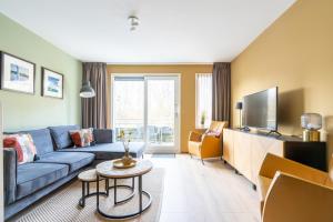 a living room with a blue couch and a tv at Appartement De Bosrand, Resort Amelander Kaap in Hollum