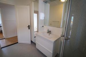 a white bathroom with a sink and a mirror at Spacious 3-Bedroom Apartment with Comfy Beds in Central Vágur, Island of Suðuroy in Vágur +33 photos