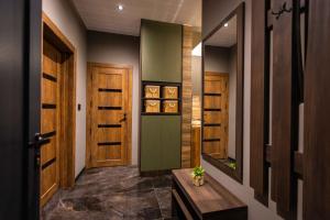 a hallway with wooden doors and a mirror at Apartman ALPINA Bogatic in Bogatić