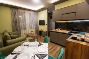 a kitchen and living room with a table with wine glasses at Apartman ALPINA Bogatic in Bogatić