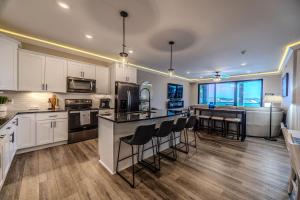 a kitchen with white cabinets and a bar with stools at Family Tides Condo for 8 in Osage Beach