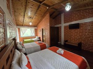 a bedroom with two beds and a brick wall at Hostería Agoyan Deluxe in Ulba