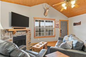 a living room with couches and a flat screen tv at Blue Sky Lodge For 4 in Branson West