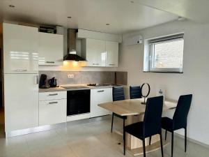 a kitchen with white cabinets and a wooden table and chairs at Le Paradis d'Ayli in Aywaille