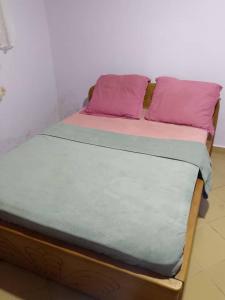 a bed with pink and purple pillows on it at La casa in Kribi